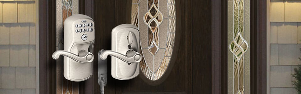 Keypad deadbolt and lever handle on a dark entry door with decorative glass