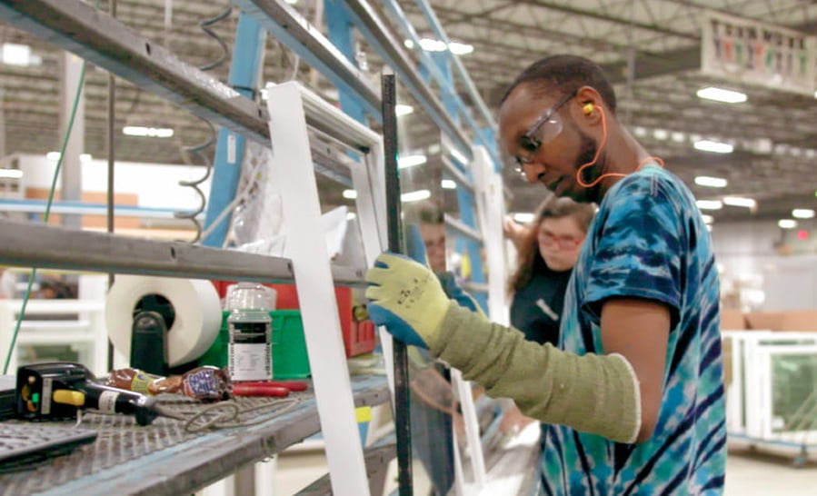 Worker in safety glasses assembling a window frame on the production floor