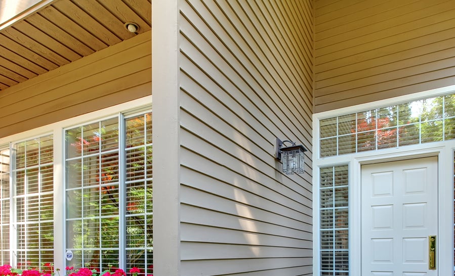 Horizontal lap siding running along a covered porch beside a white entry door