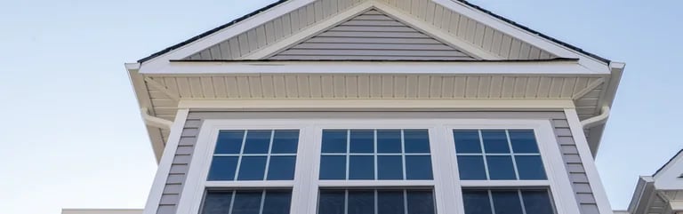 Low-angle view of a gabled dormer with a wide multi-pane bay window