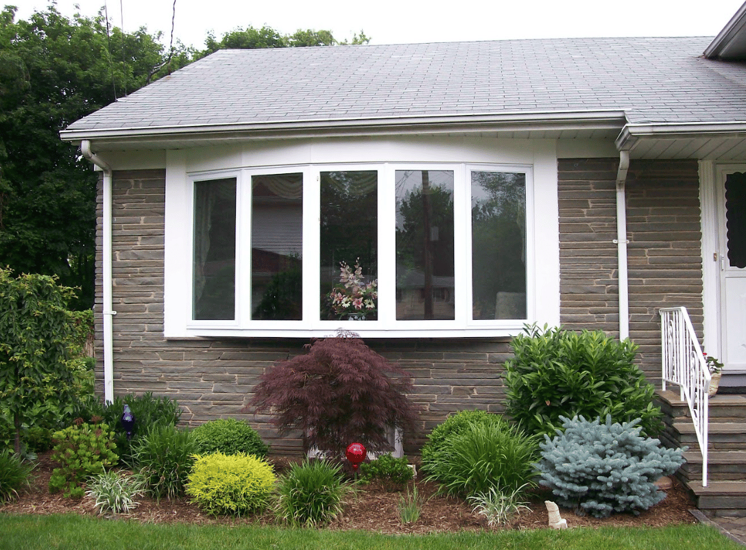 bay windows on exterior of home above flower bed