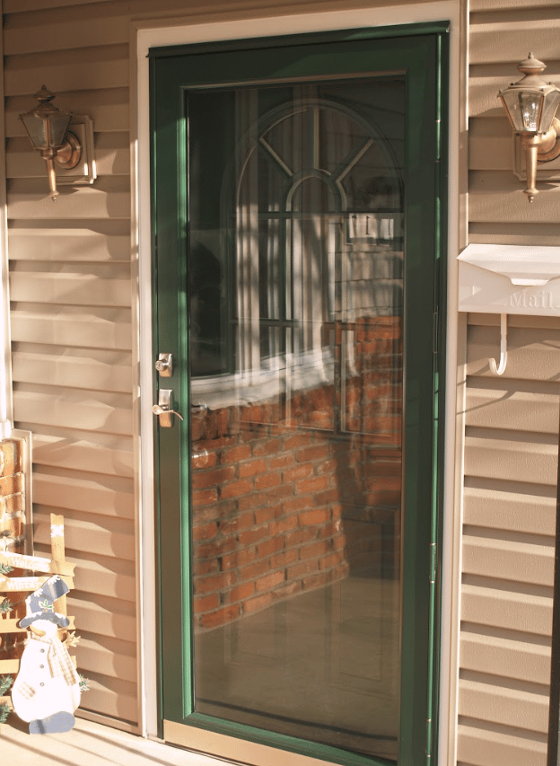 Exterior front entryway featuring a wood-grain glass panel front door with white sidelights and an arched transom window, set into a red brick house wall with wall lanterns and potted flowers.